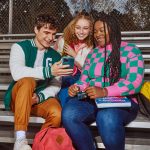 Teens sitting on bleachers using the Greenlight app